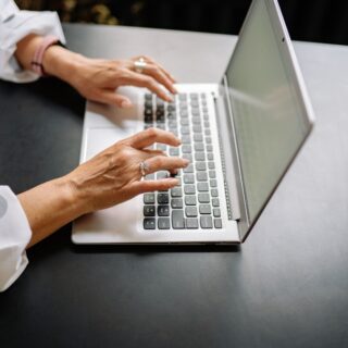 Woman working on a laptop at a desk, focused on her screen in a bright and professional workspace.
