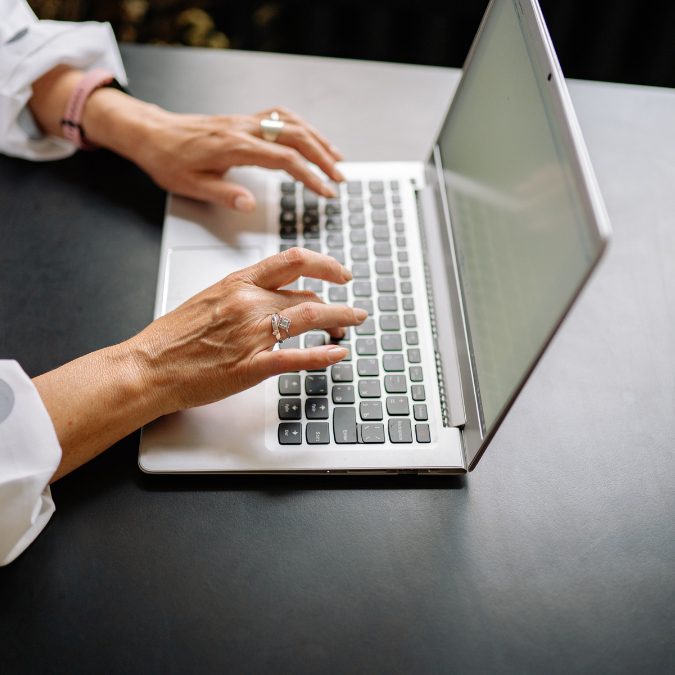 Woman working on a laptop at a desk, focused on her screen in a bright and professional workspace.
